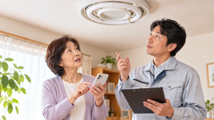 古い蛍光灯器具の交換について電気工事業者に相談する女性